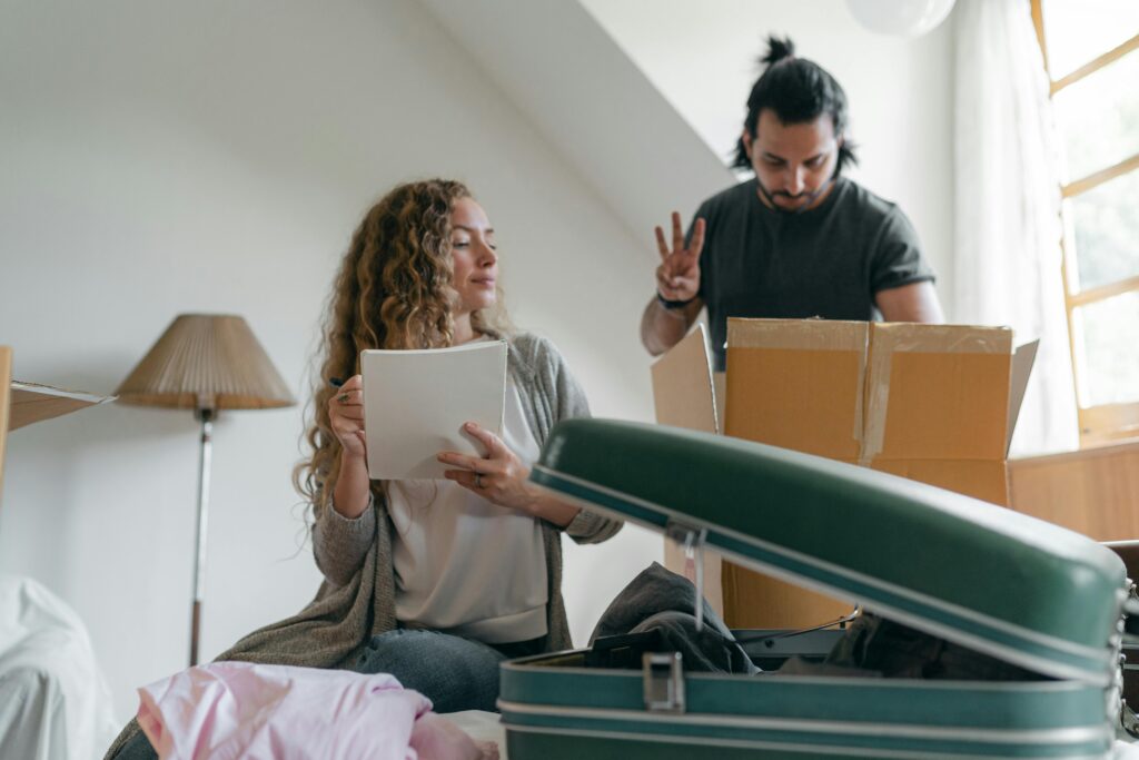 A couple happily packs boxes in their bright, cozy bedroom, preparing for a move.